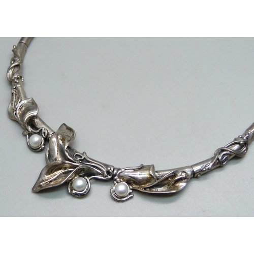 1008 - A silver Art Nouveau style necklace set with pearls, a white metal brooch and a silver bangle, dente... 