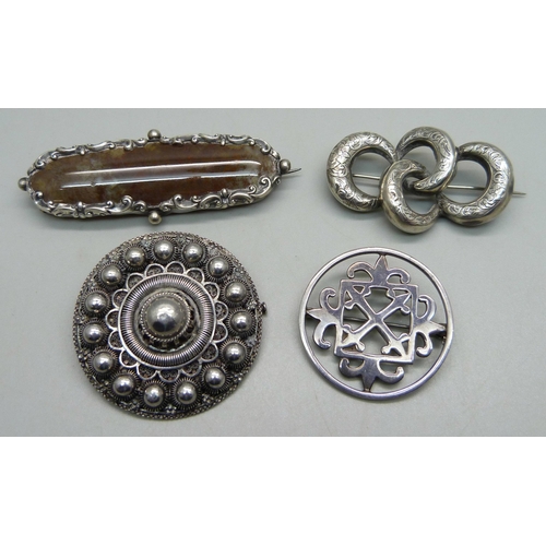 1043 - A hallmarked fretwork circular silver brooch, and three unmarked white metal brooches including a fi... 