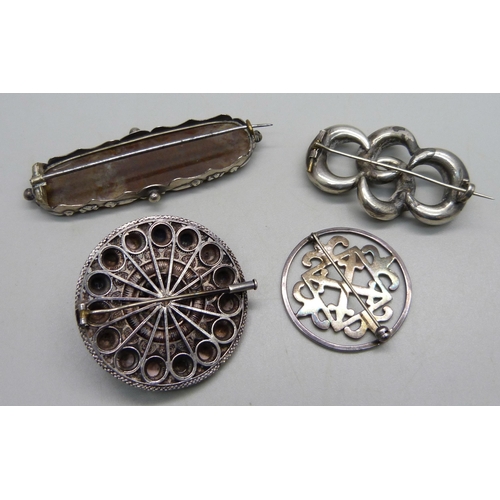 1043 - A hallmarked fretwork circular silver brooch, and three unmarked white metal brooches including a fi... 