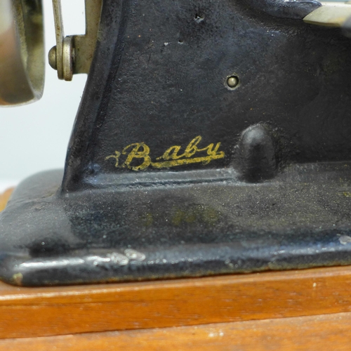 686 - An early child's sewing machine in tin holder, in working order