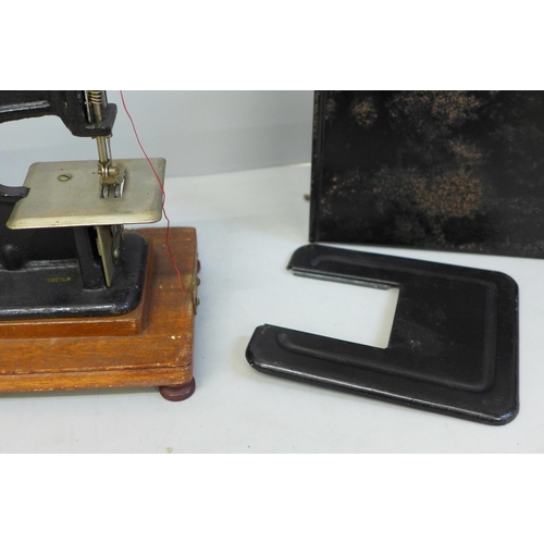 686 - An early child's sewing machine in tin holder, in working order