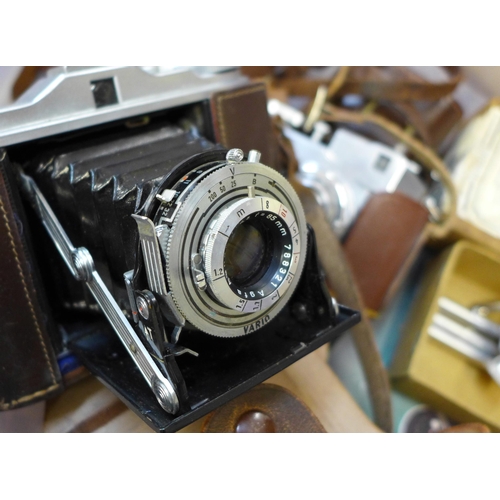 721 - A box of vintage photographic equipment; four cameras, a Komura 3.5 135mm lens, tripod and light met... 