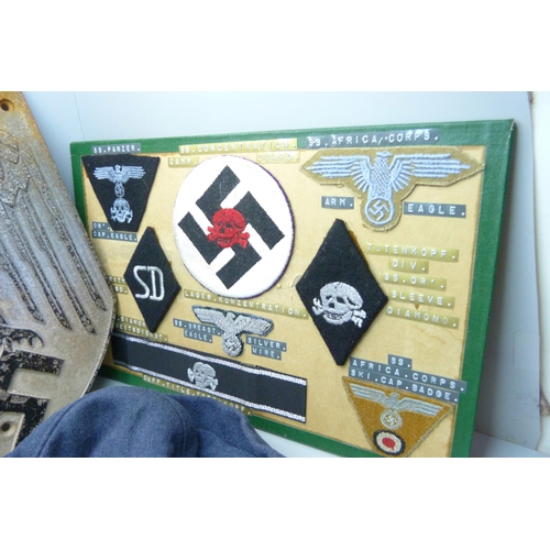 831 - A German WWII metal plaque, cap, mounted cloth badges, etc.