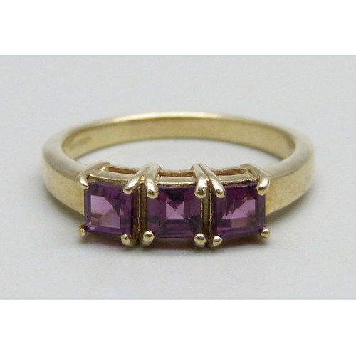 943 - A 9ct gold ring set with three square cut purple stones, 2.65g, N