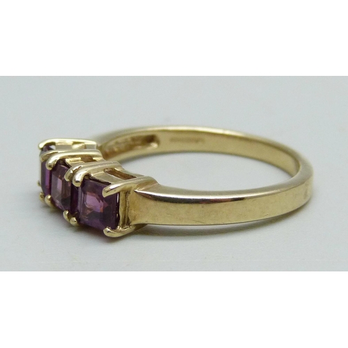 943 - A 9ct gold ring set with three square cut purple stones, 2.65g, N