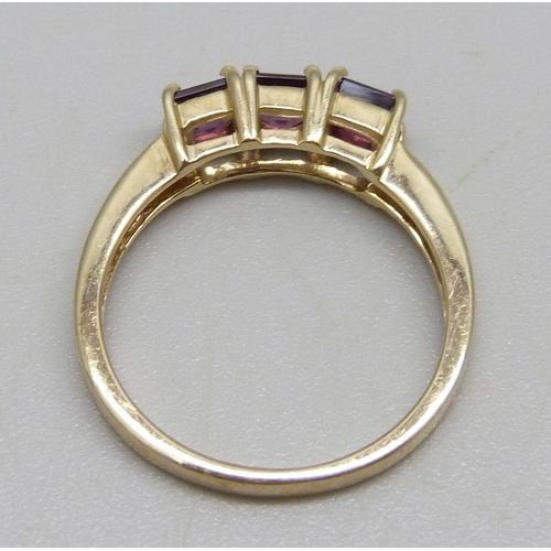 943 - A 9ct gold ring set with three square cut purple stones, 2.65g, N