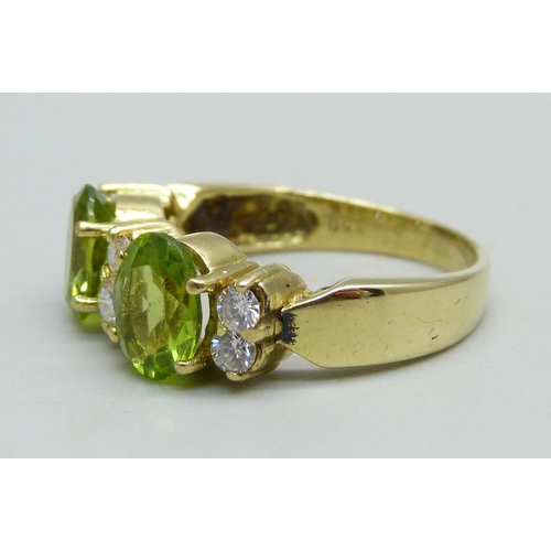 961 - An 18ct gold ring set with two peridot stones and six diamonds, 6.4g, P