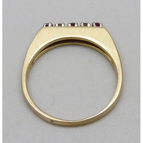 987 - An 18ct gold ring set with three red stones and two diamonds, 3.2g, O