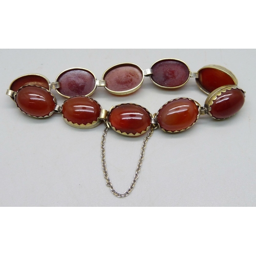 990 - A .900 silver gilt bracelet set with cabochon red stone panels, one setting a/f, 22g