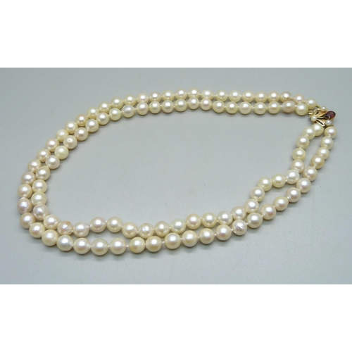 993 - A double row pearl necklace with 9ct gold clasp set with a garnet and two pearls, 40.5cm, 62g