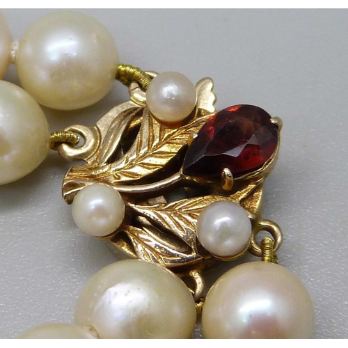 993 - A double row pearl necklace with 9ct gold clasp set with a garnet and two pearls, 40.5cm, 62g