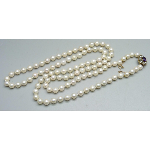 994 - A long pearl necklace with 9ct gold clasp set with an amethyst and pearls, 83cm, 47g