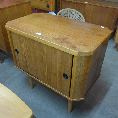 54 - A small teak sliding two door octagonal cupboard