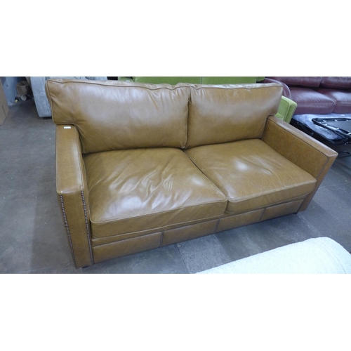 1490 - A tan vintage leather two and a half seater sofa with studwork, RRP £2850 * this lot is subject to V... 