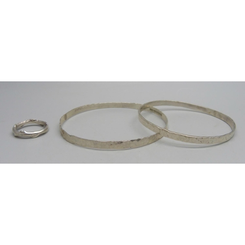 1026 - A planished silver bangle, assayed, by Andrew Elliot, a white metal bangle, and a silver organic rin... 