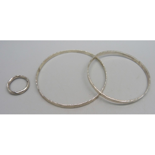 1026 - A planished silver bangle, assayed, by Andrew Elliot, a white metal bangle, and a silver organic rin... 