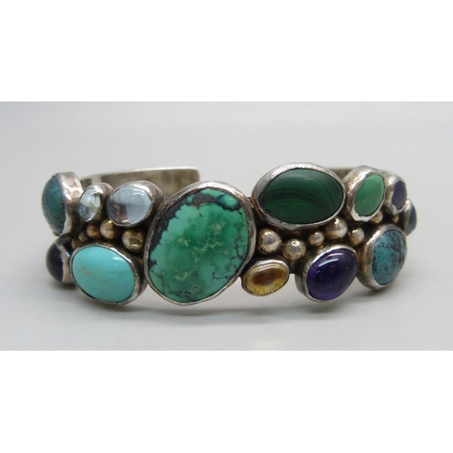 1040 - A sterling silver bangle set with gemstones, 39g