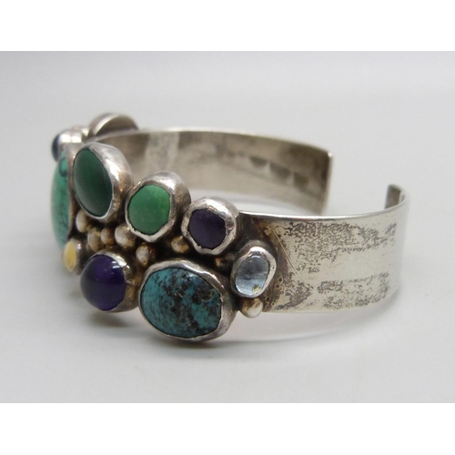 1040 - A sterling silver bangle set with gemstones, 39g