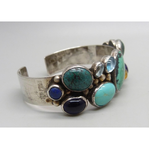 1040 - A sterling silver bangle set with gemstones, 39g