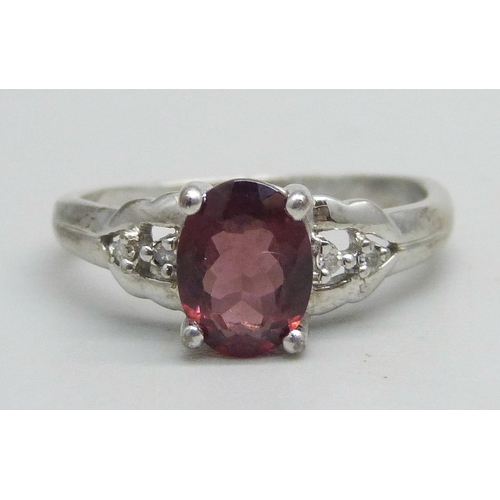 1062 - A 9k white gold ring set with a garnet and four diamonds, 2.2g, M