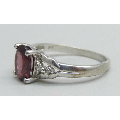 1062 - A 9k white gold ring set with a garnet and four diamonds, 2.2g, M