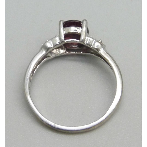 1062 - A 9k white gold ring set with a garnet and four diamonds, 2.2g, M