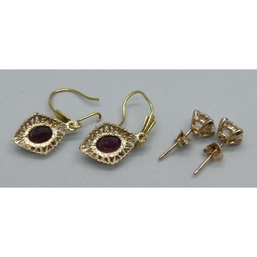 1121 - A pair of 9ct gold and garnet drop earrings, and a pair of yellow metal and white stone stud earring... 