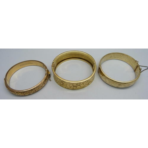 1127 - A rolled gold bangle, a 9ct metal core bangle and a gold plated bangle