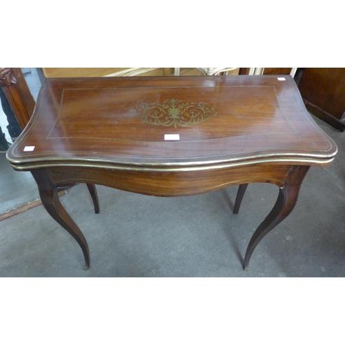 134 - A 19th Century mahogany and brass inlaid serpentine fold over games table