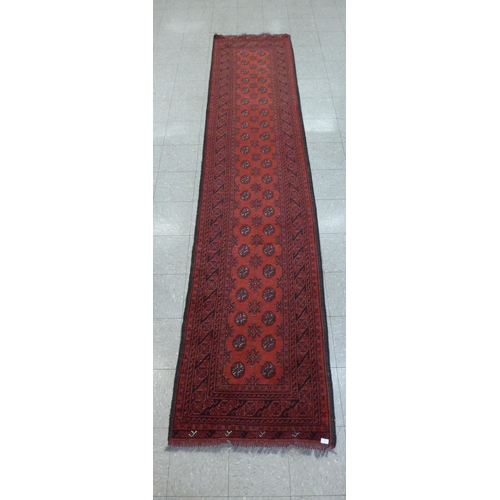 184 - An eastern red ground runner rug 88cmx397cm