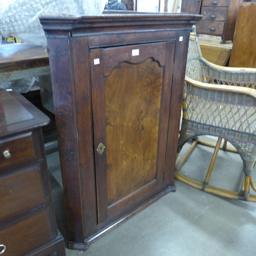 231 - A George III oak splay front wall haning corner cupboard