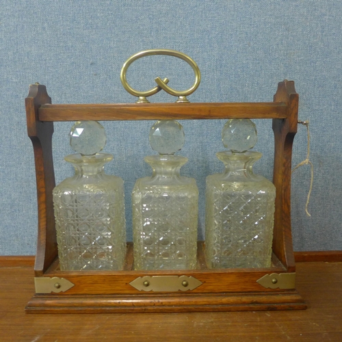 367 - An early 20th Century oak and E.P.N.S mounted tantalus, with three glass decanters