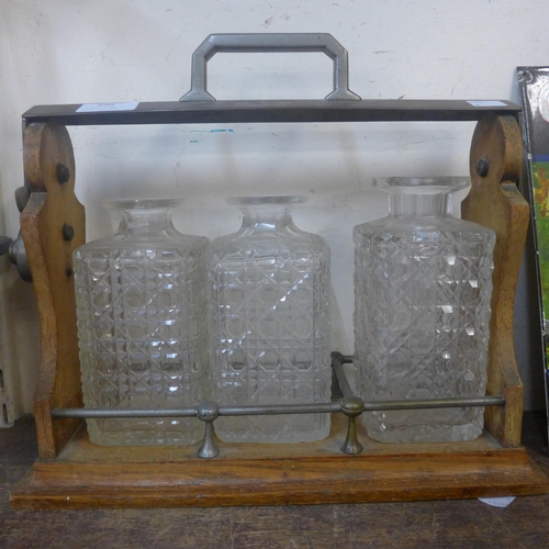 390 - An early 20th Century oak and brass mounted tantalus (locked and decanters lacking stoppers)