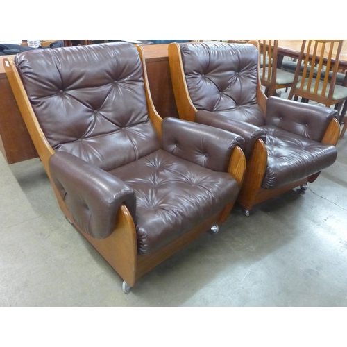 63 - A pair of G-Plan teak and burgundy leather Saddle armchairs. Please note this lot is being sold as a... 