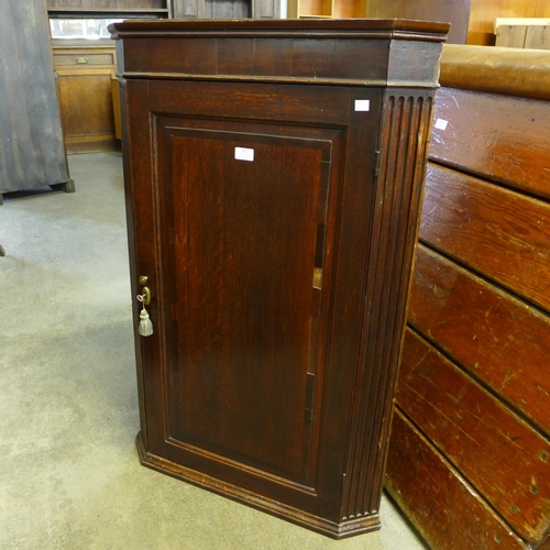 227 - A George III oak splay front wall hanging corner cupboard