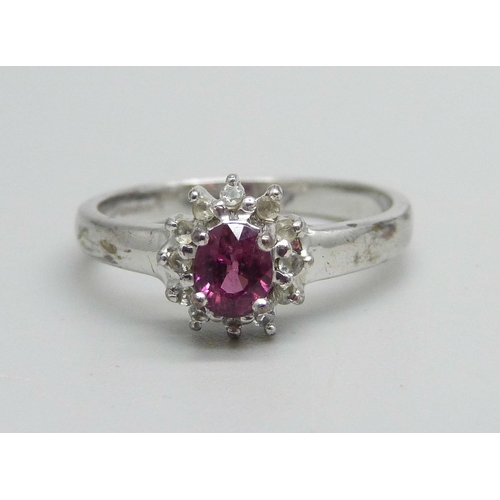 1018 - A 9ct white gold ring set with a garnet and white stone halo, 2.7g, N/O