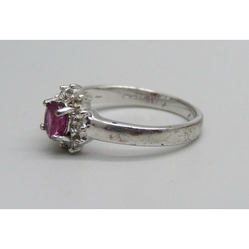 1018 - A 9ct white gold ring set with a garnet and white stone halo, 2.7g, N/O