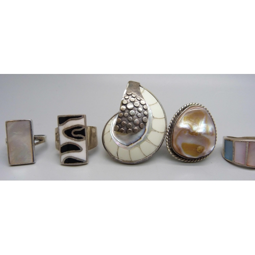 1054 - Eight chunky large silver rings set with mother of pearl, and one silver ring set with a fossil, 88g