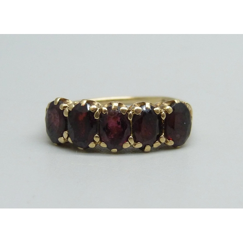 1091 - A 9ct gold ring set with five garnets, 2.7g, O