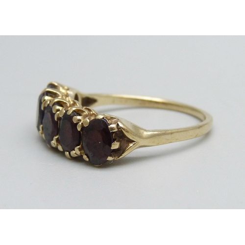 1091 - A 9ct gold ring set with five garnets, 2.7g, O