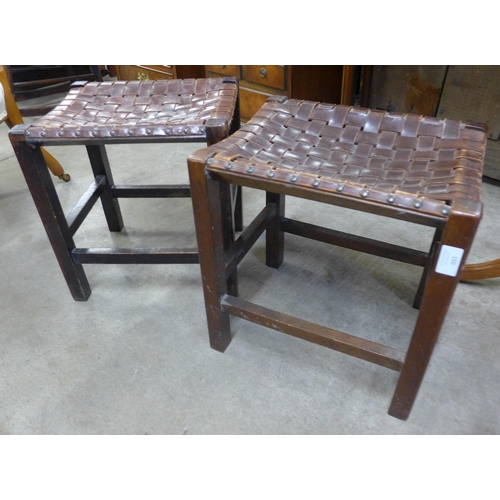 150 - A pair of Arts and Crafts oak and leather strapwork stools