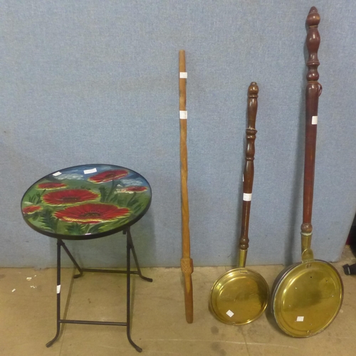 289 - A small glass topped folding occasional table, two brass warming pans and a walking cane