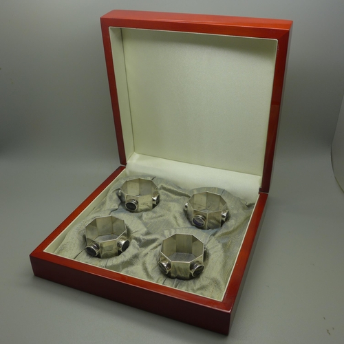 1299 - A set of four octagonal silver napkin rings in the Arts and Crafts style set with roundels of Blue J... 