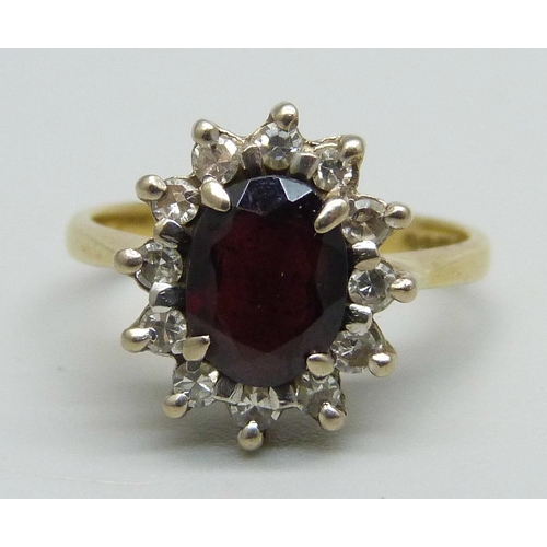 1047 - An 18ct gold ring set with a garnet and diamond halo, 4.3g, K