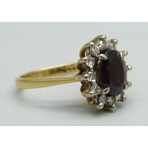 1047 - An 18ct gold ring set with a garnet and diamond halo, 4.3g, K