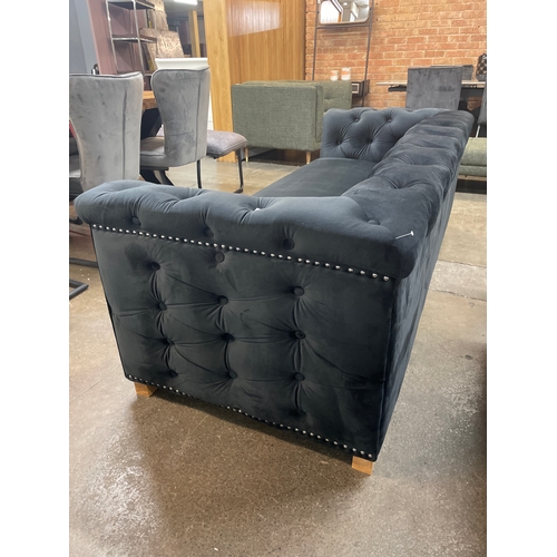 1472 - A black velvet upholstered buttoned three seater sofa