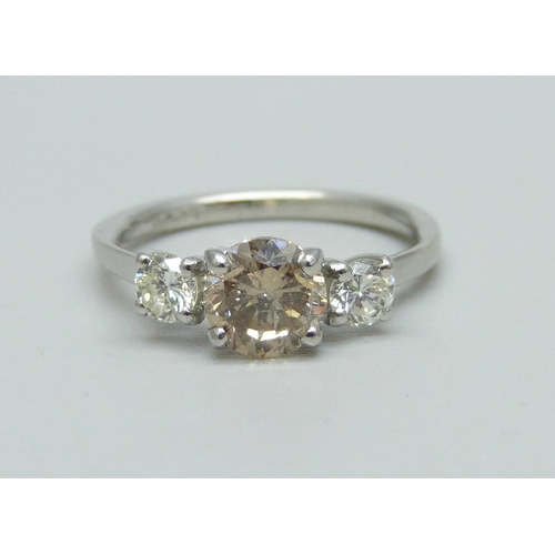 1002 - A hallmarked platinum, three stone diamond ring, champagne coloured centre diamond with two white di... 