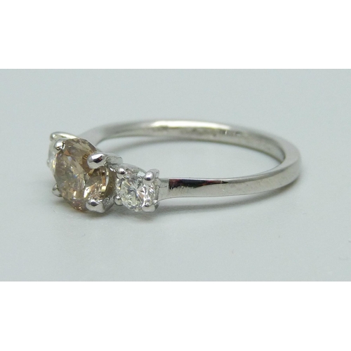 1002 - A hallmarked platinum, three stone diamond ring, champagne coloured centre diamond with two white di... 