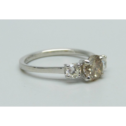 1002 - A hallmarked platinum, three stone diamond ring, champagne coloured centre diamond with two white di... 