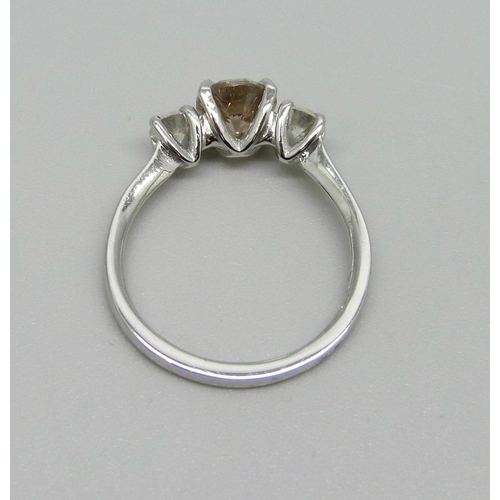 1002 - A hallmarked platinum, three stone diamond ring, champagne coloured centre diamond with two white di... 